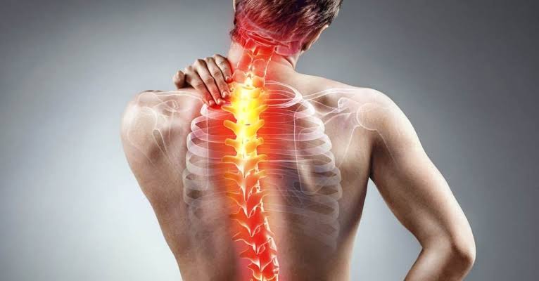 A man holding his back in pain, with an illustration of the spine highlighted in red and yellow to indicate discomfort or inflammation.